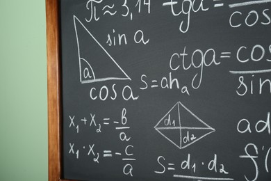 Photo of Chalkboard with many different math formulas on green wall, closeup