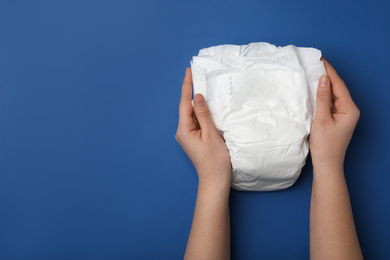 Photo of Woman with diaper on blue background, closeup. Space for text