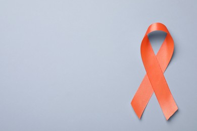Photo of Orange ribbon on light grey background, top view with space for text. Multiple sclerosis awareness