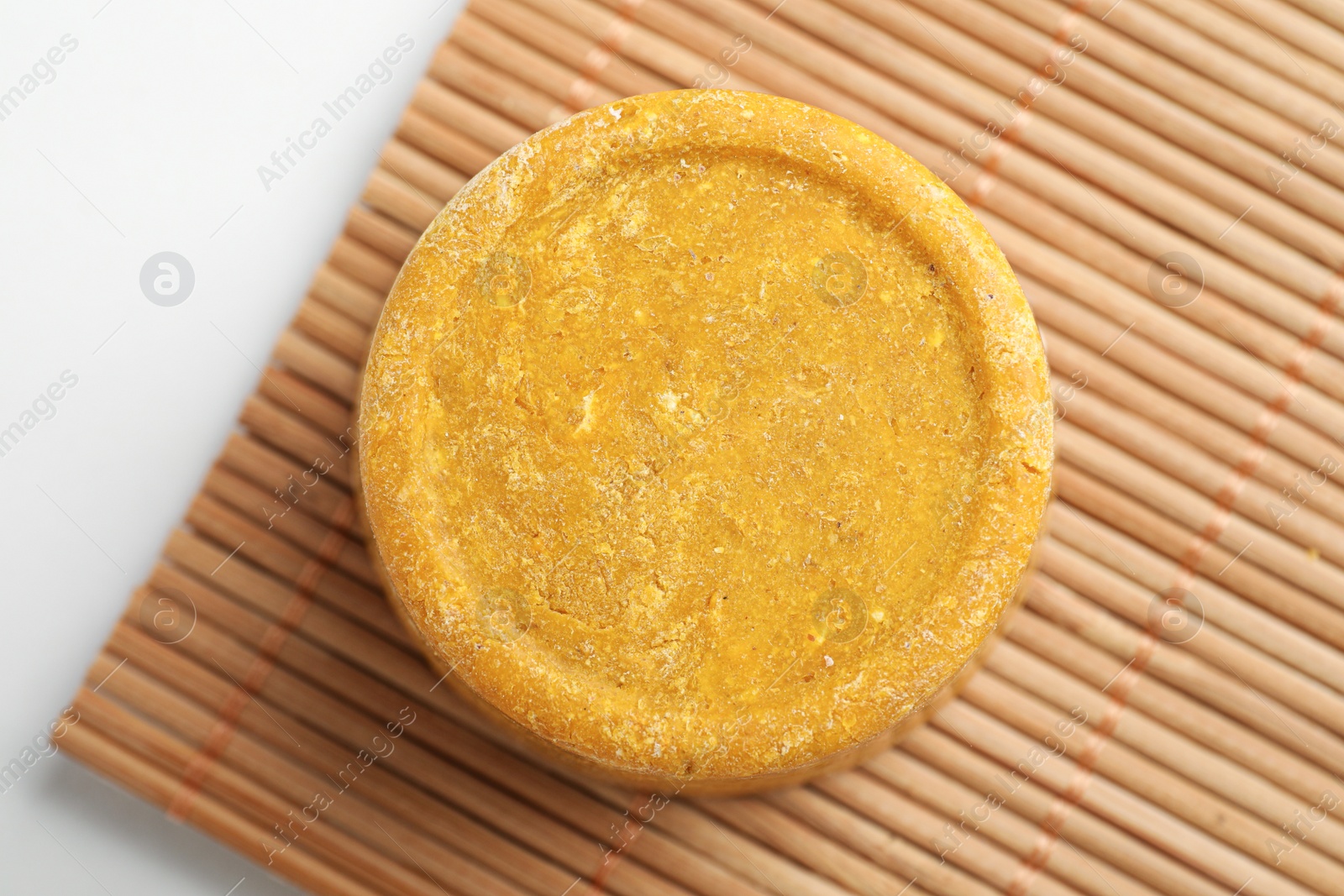 Photo of Yellow solid shampoo bar on light table, top view