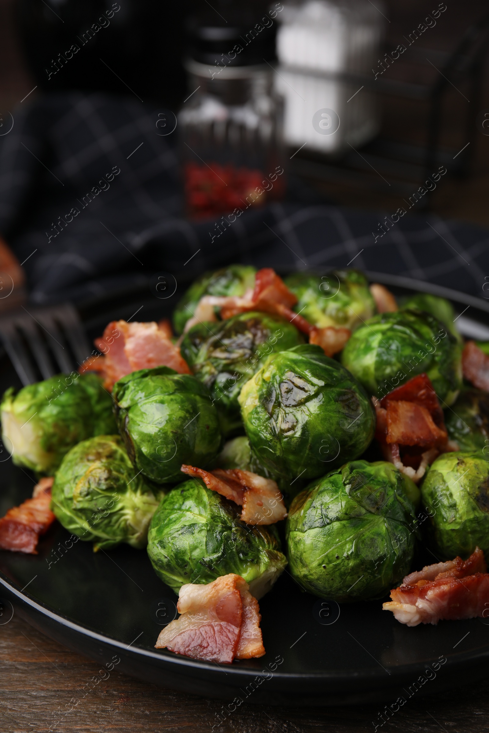 Photo of Delicious roasted Brussels sprouts and bacon on wooden table, closeup
