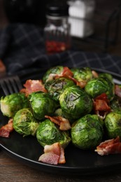 Photo of Delicious roasted Brussels sprouts and bacon on wooden table, closeup