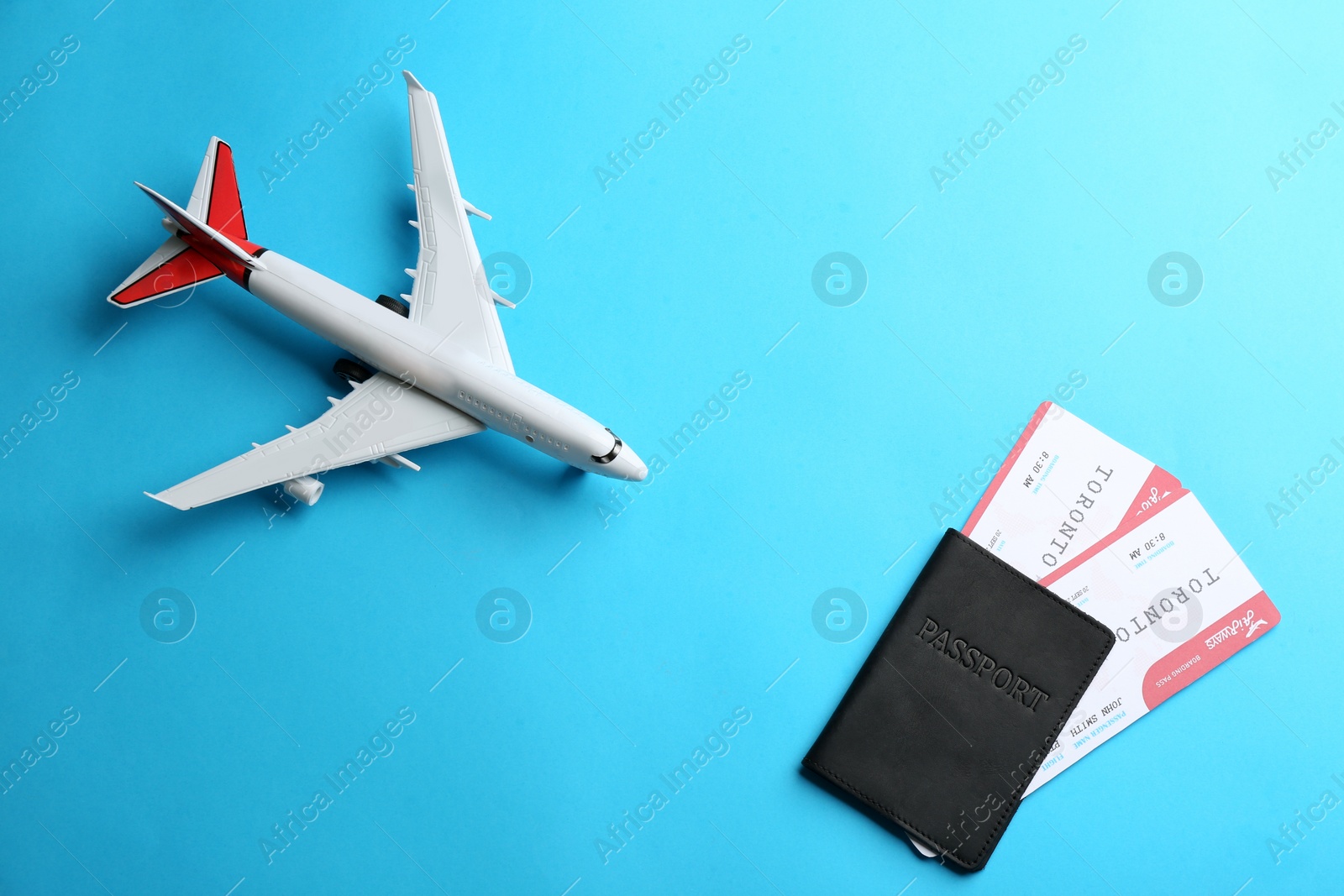 Photo of Toy airplane and passport with tickets on light blue background, flat lay