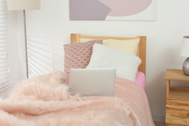 Stylish teenager's room interior with comfortable bed and laptop