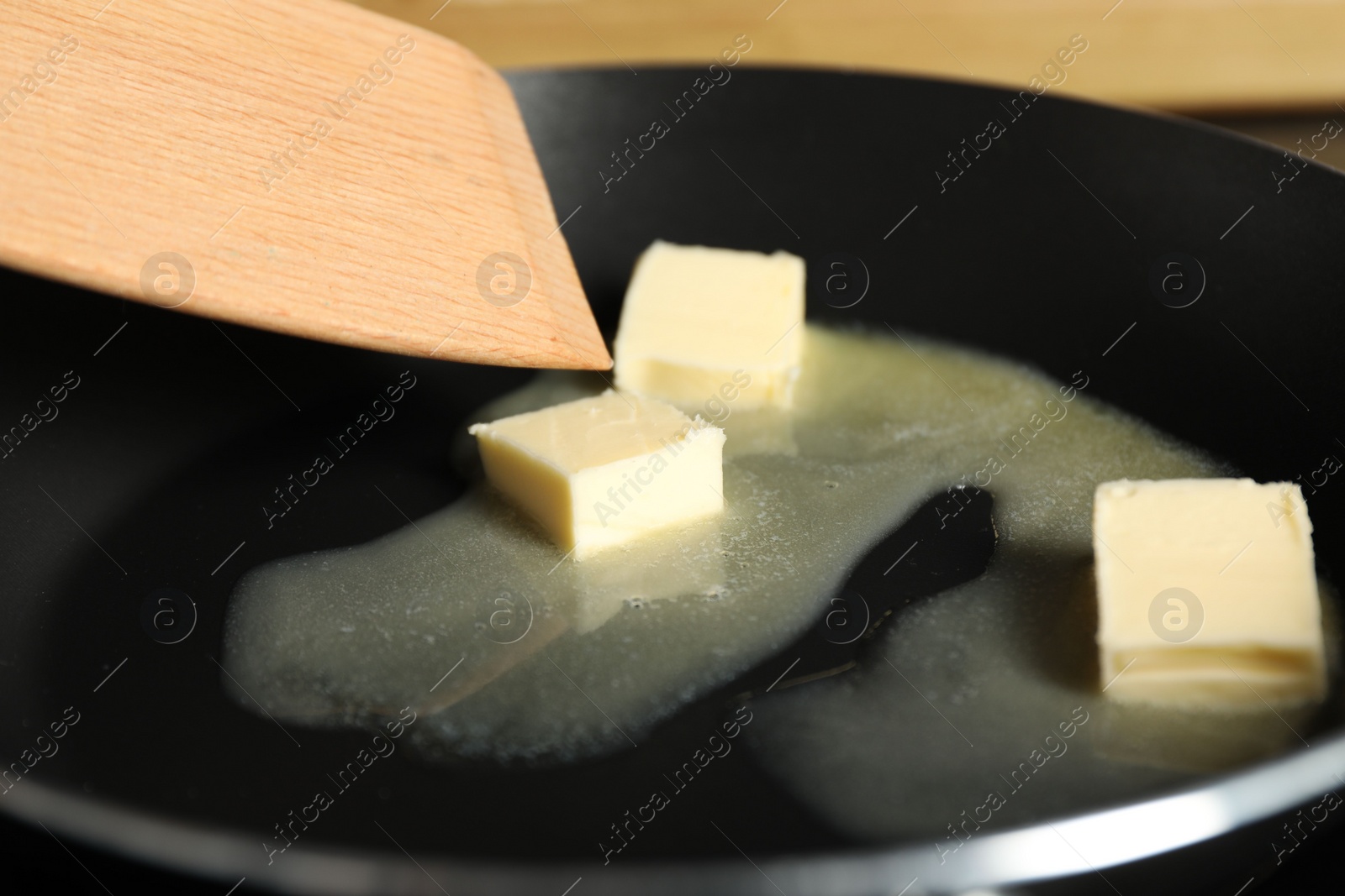 Photo of Stirring melting butter in frying pan, closeup