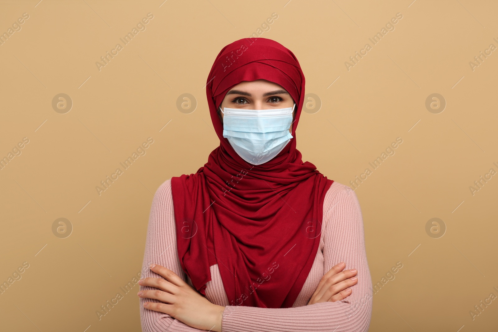 Photo of Muslim woman in hijab and medical mask on beige background