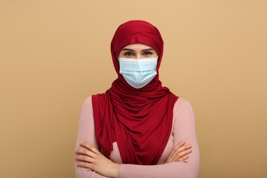 Muslim woman in hijab and medical mask on beige background