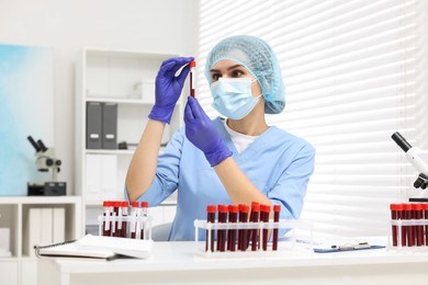 Laboratory testing. Doctor with blood samples in tubes at white table indoors