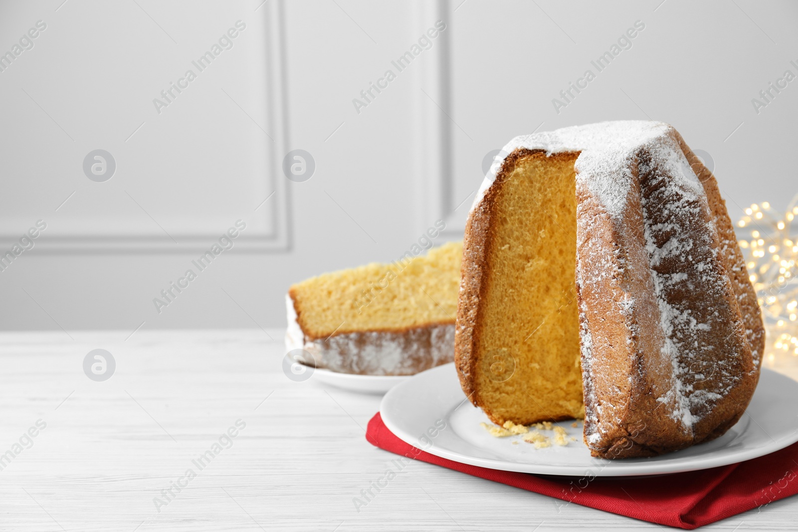 Photo of Delicious Pandoro cake decorated with powdered sugar on white wooden table, space for text. Traditional Italian pastry