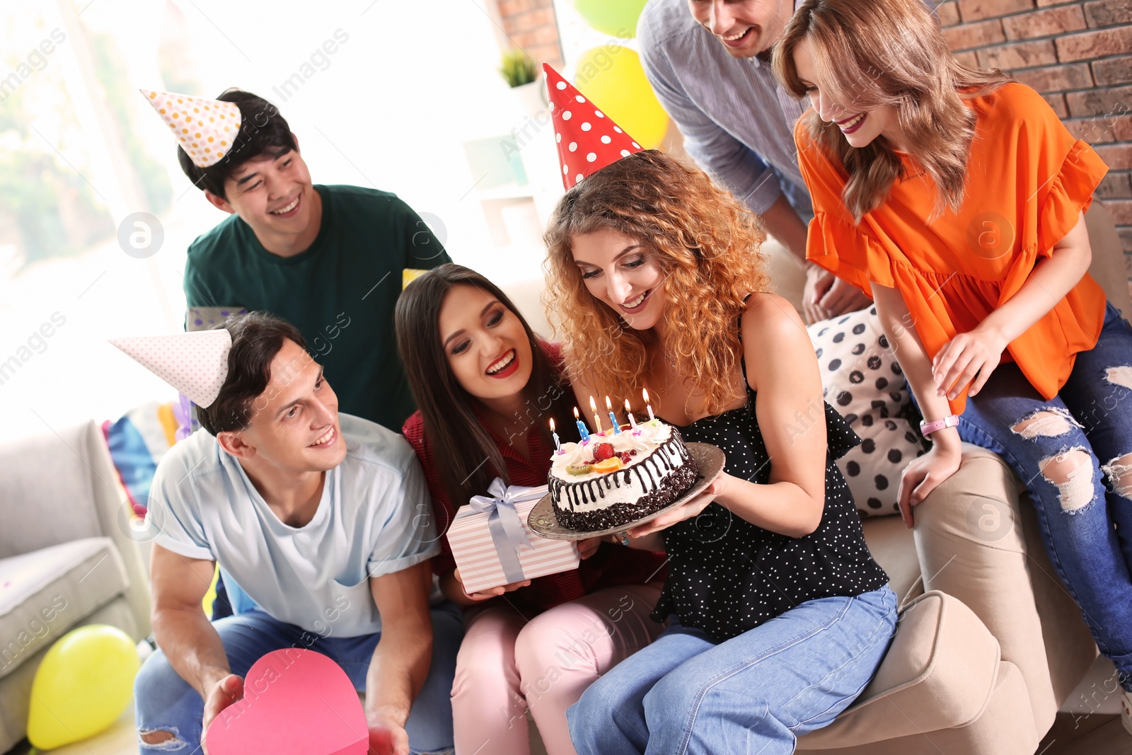 Photo of Young people celebrating birthday with tasty cake indoors