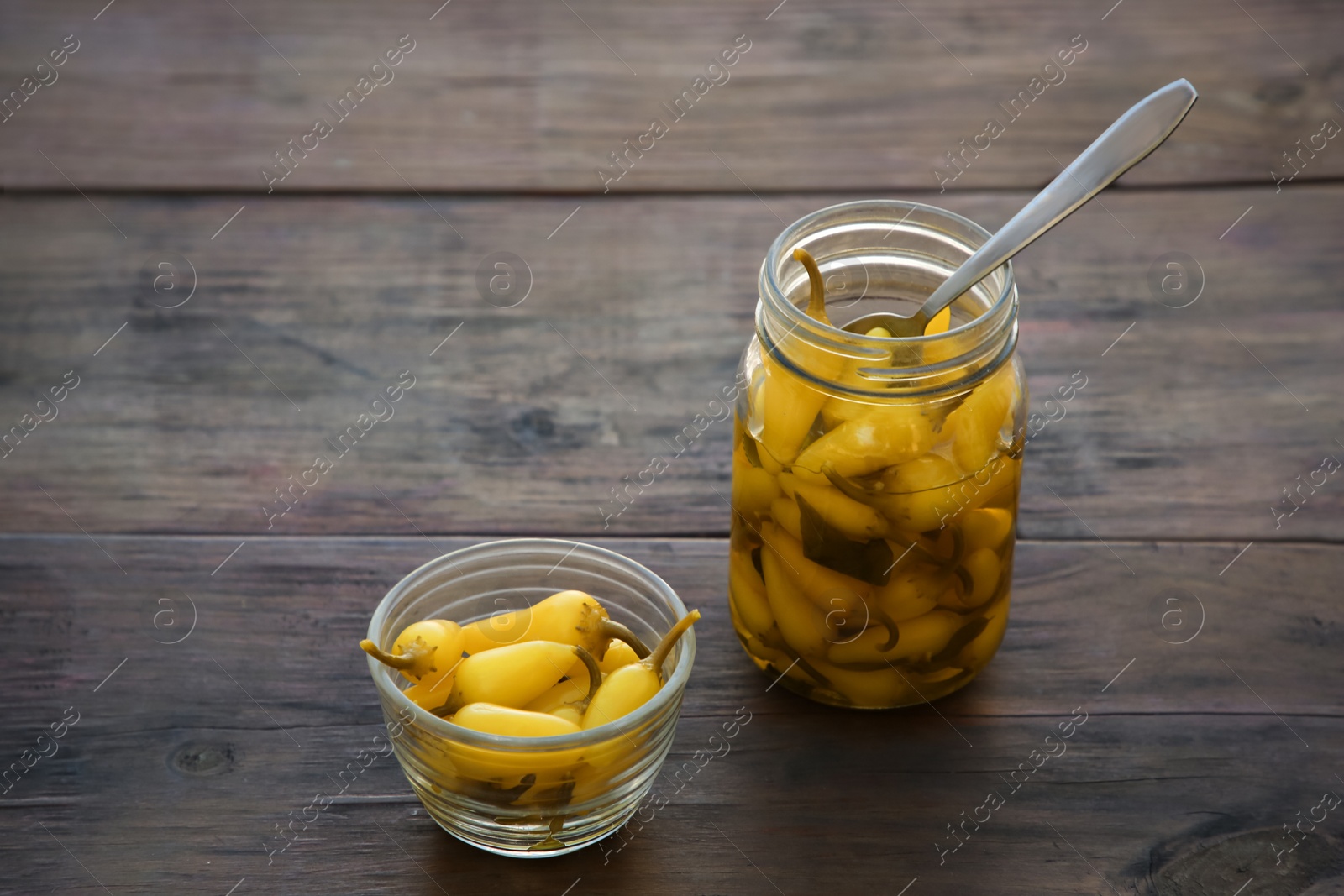 Photo of Pickled yellow jalapeno peppers on wooden table. Space for text