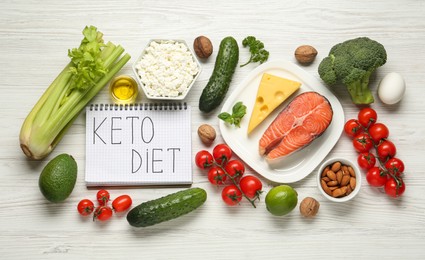 Photo of Notebook with phrase Keto Diet and different products on white wooden table, flat lay