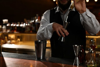 Bartender making fresh alcoholic cocktail at bar counter, closeup. Space for text