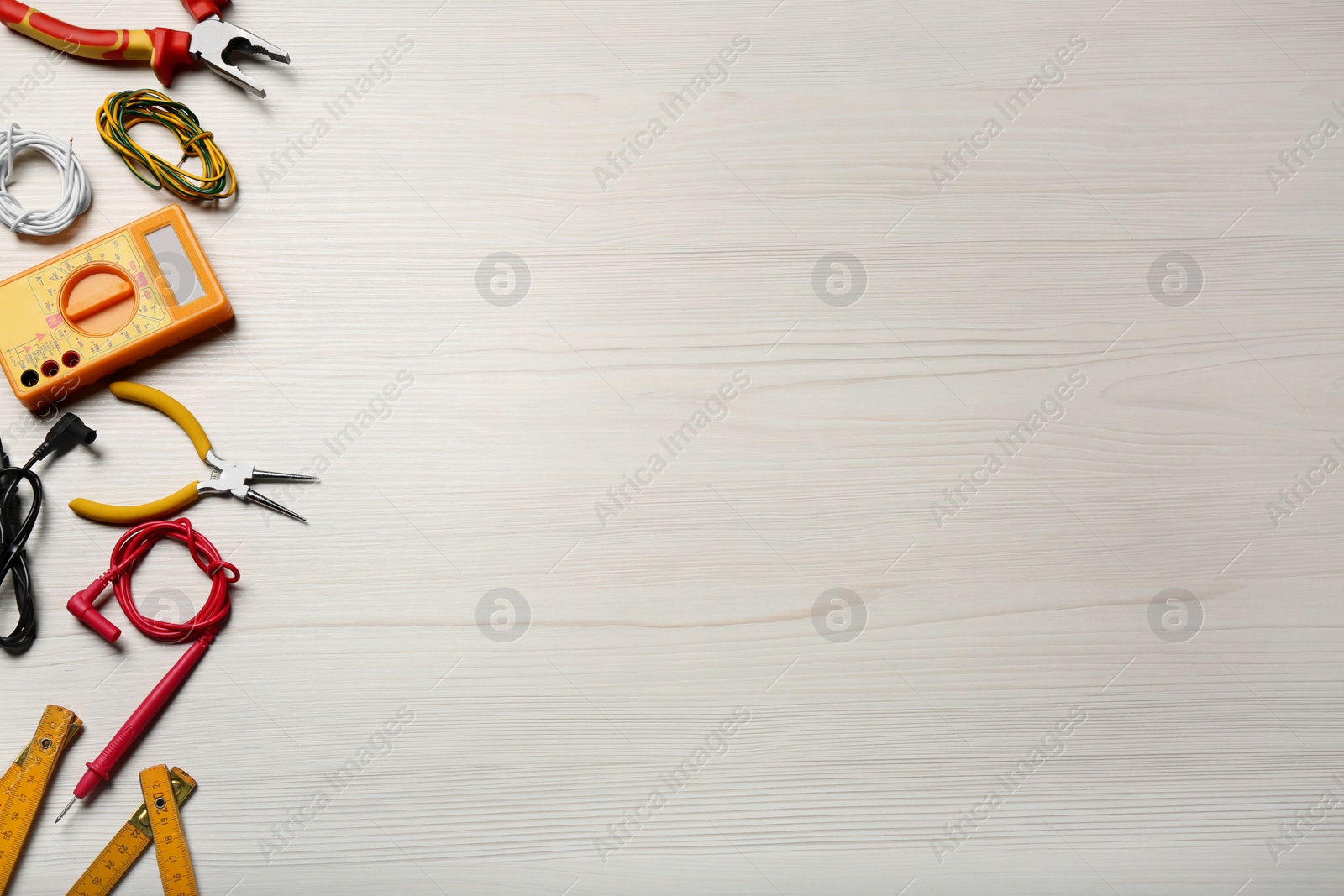 Photo of Different wires and electrical tools on white wooden table, flat lay. Space for text