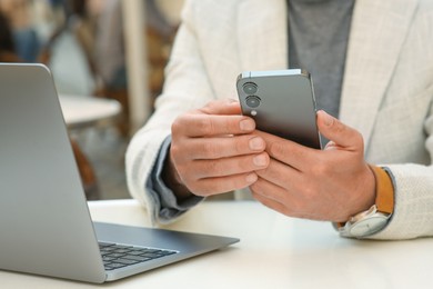 Photo of Man using smartphone at table in outdoor cafe, closeup