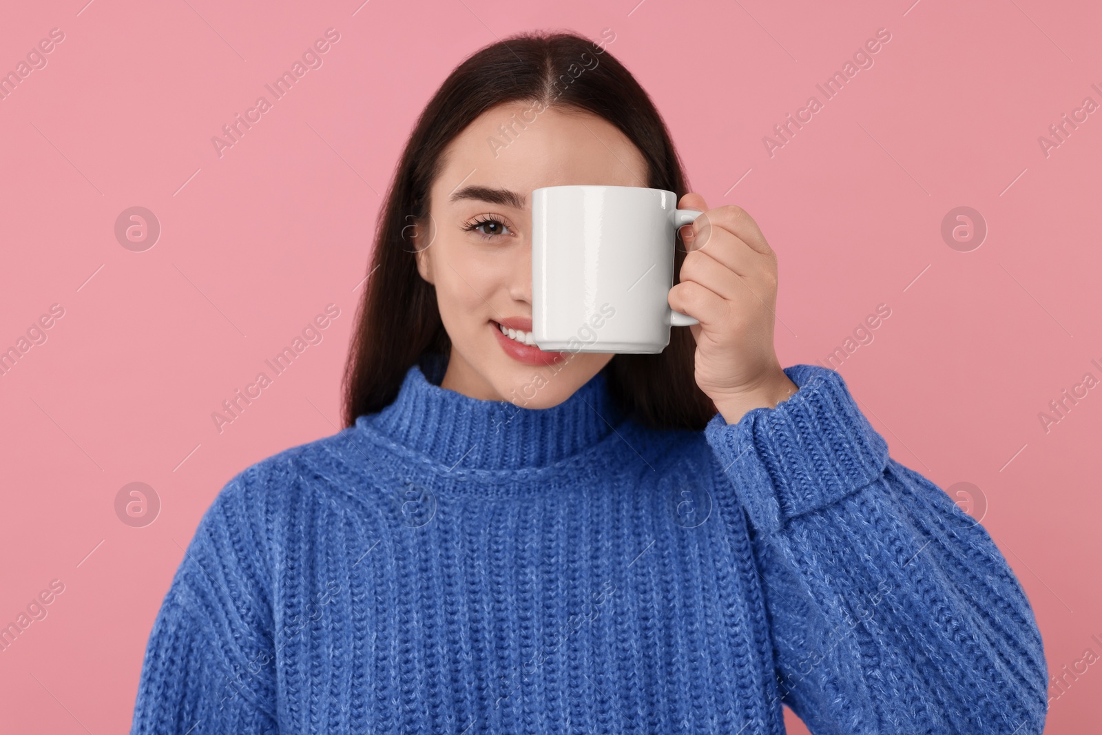 Photo of Happy young woman covering eye white ceramic mug on pink background