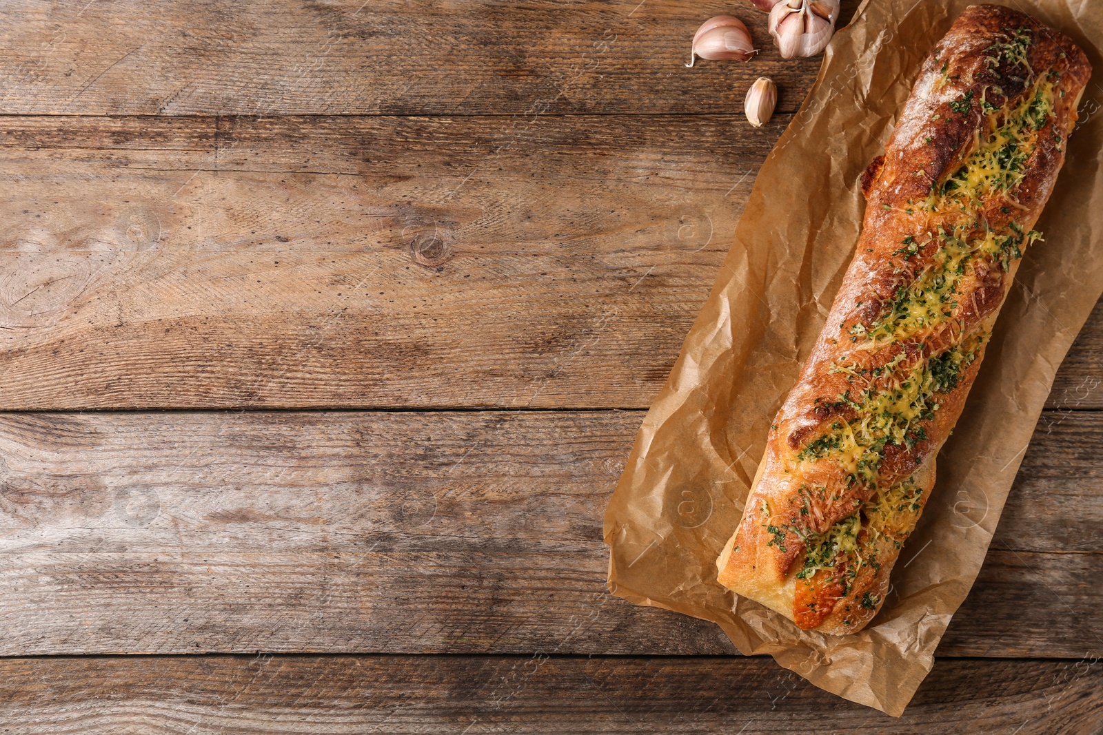 Photo of Tasty homemade garlic bread with cheese and herbs on wooden table, flat lay. Space for text