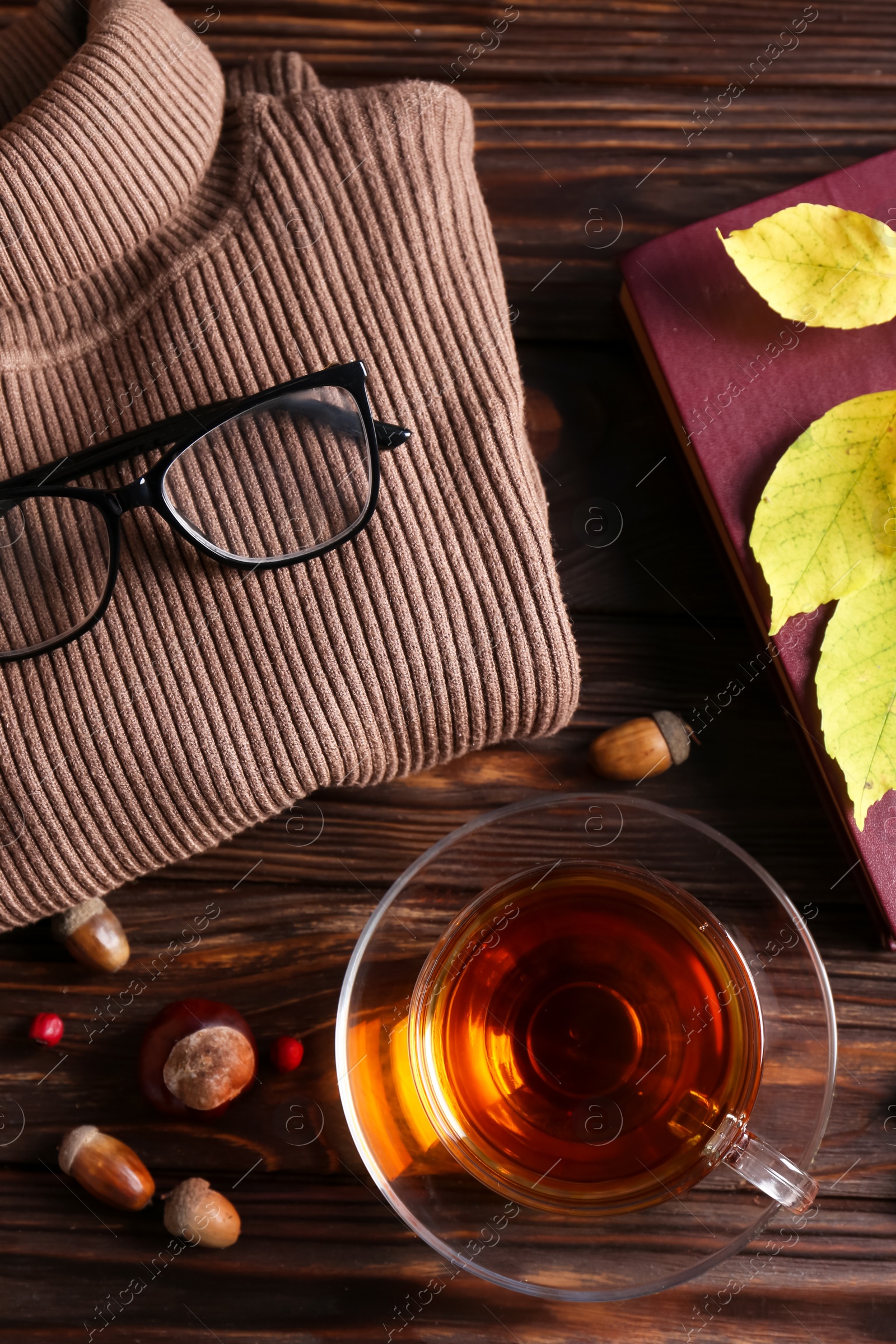 Photo of Flat lay composition with cup of aromatic tea and soft sweater on wooden table. Autumn atmosphere