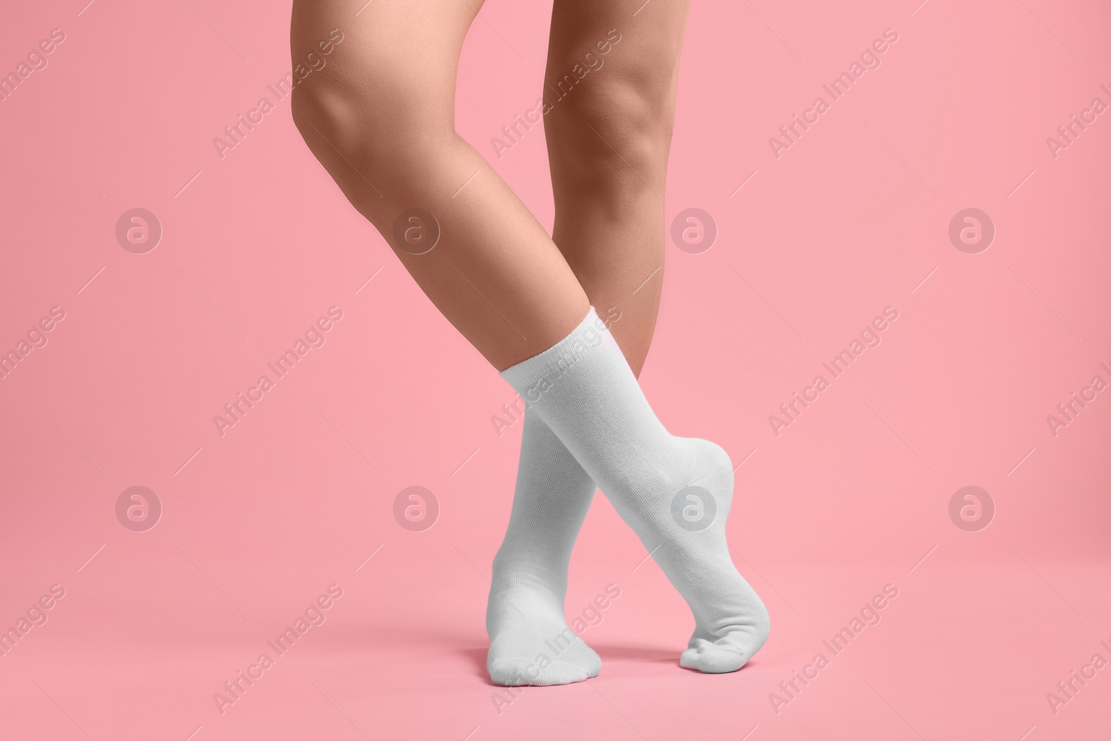 Photo of Woman in stylish white socks on pink background, closeup