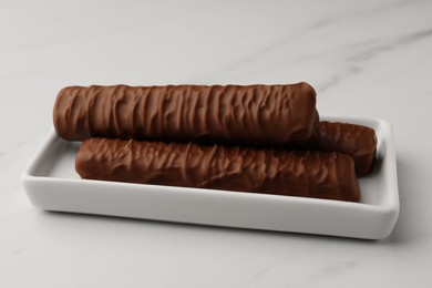 Photo of Sweet tasty chocolate bars on white marble table