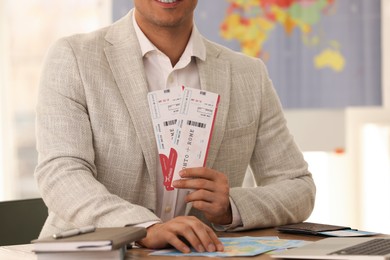 Travel agent with tickets at table in office, closeup