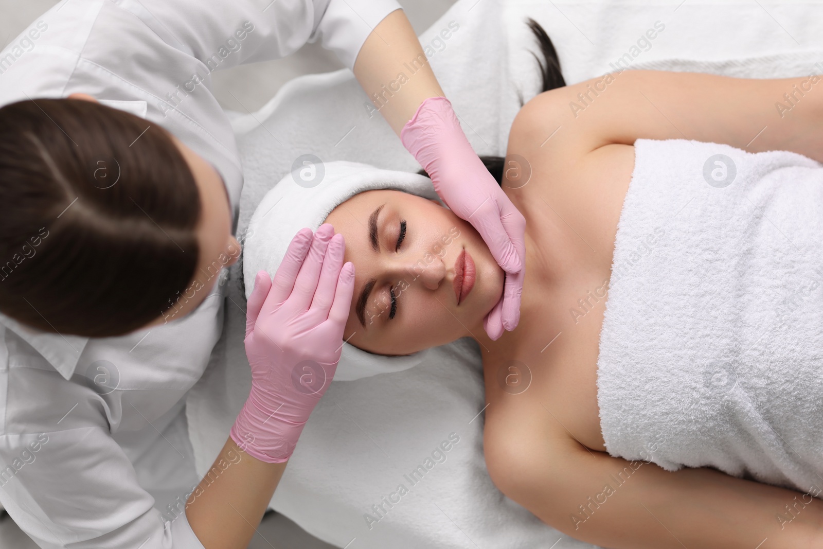 Photo of Cosmetologist making face massage to client, top view