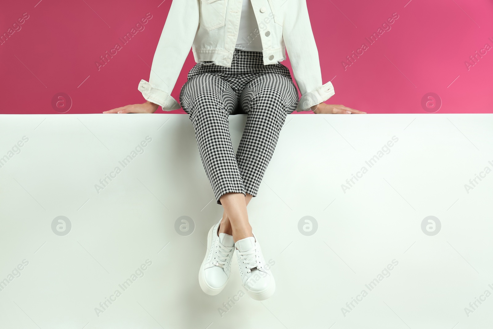 Photo of Woman in stylish shoes sitting on color background, closeup