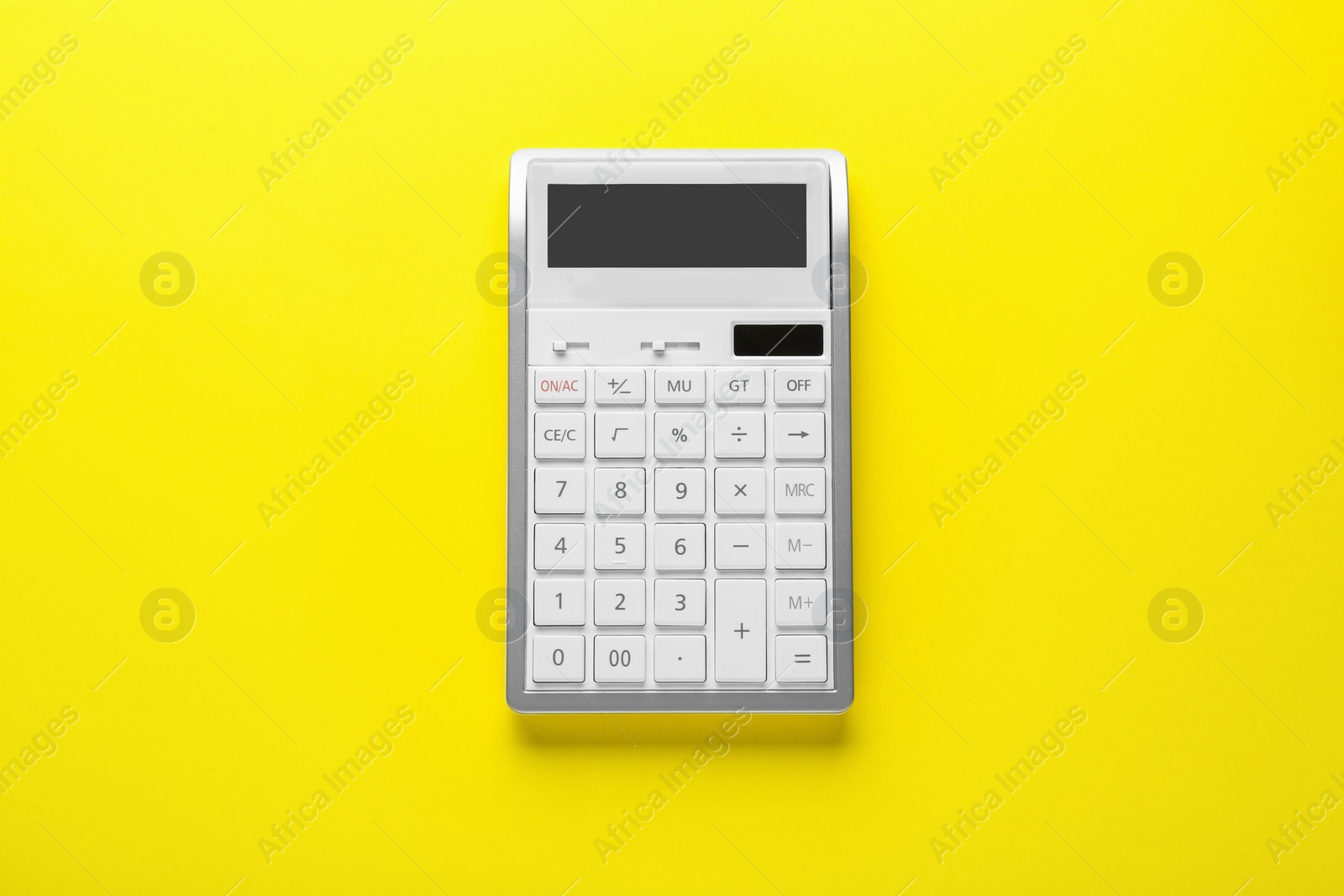 Photo of White calculator on yellow background, top view