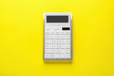 White calculator on yellow background, top view