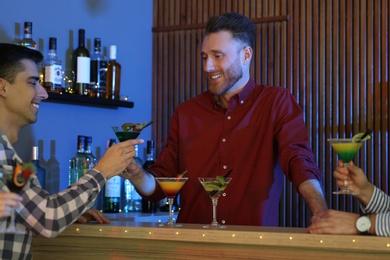 Photo of Young man taking martini cocktail from barman at party