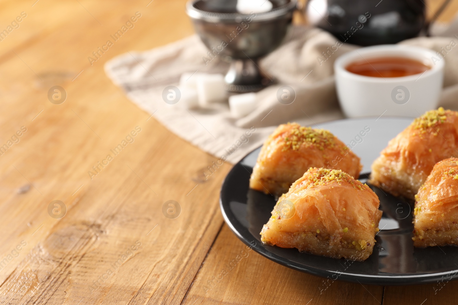 Photo of Delicious sweet baklava with pistachios on wooden table, closeup. Space for text