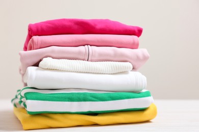 Photo of Stack of folded clothes on table against beige background
