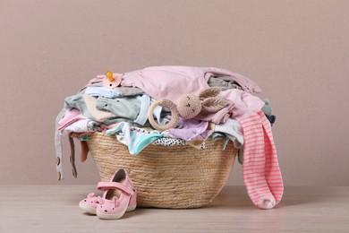 Photo of Laundry basket with baby clothes and shoes on wooden table