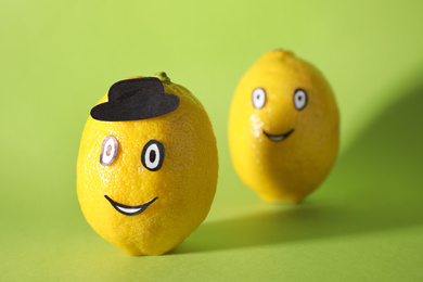 Photo of Lemons with drawn faces on green background. Concept of jealousy
