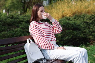 Photo of Woman with napkin suffering from seasonal allergy on bench in park