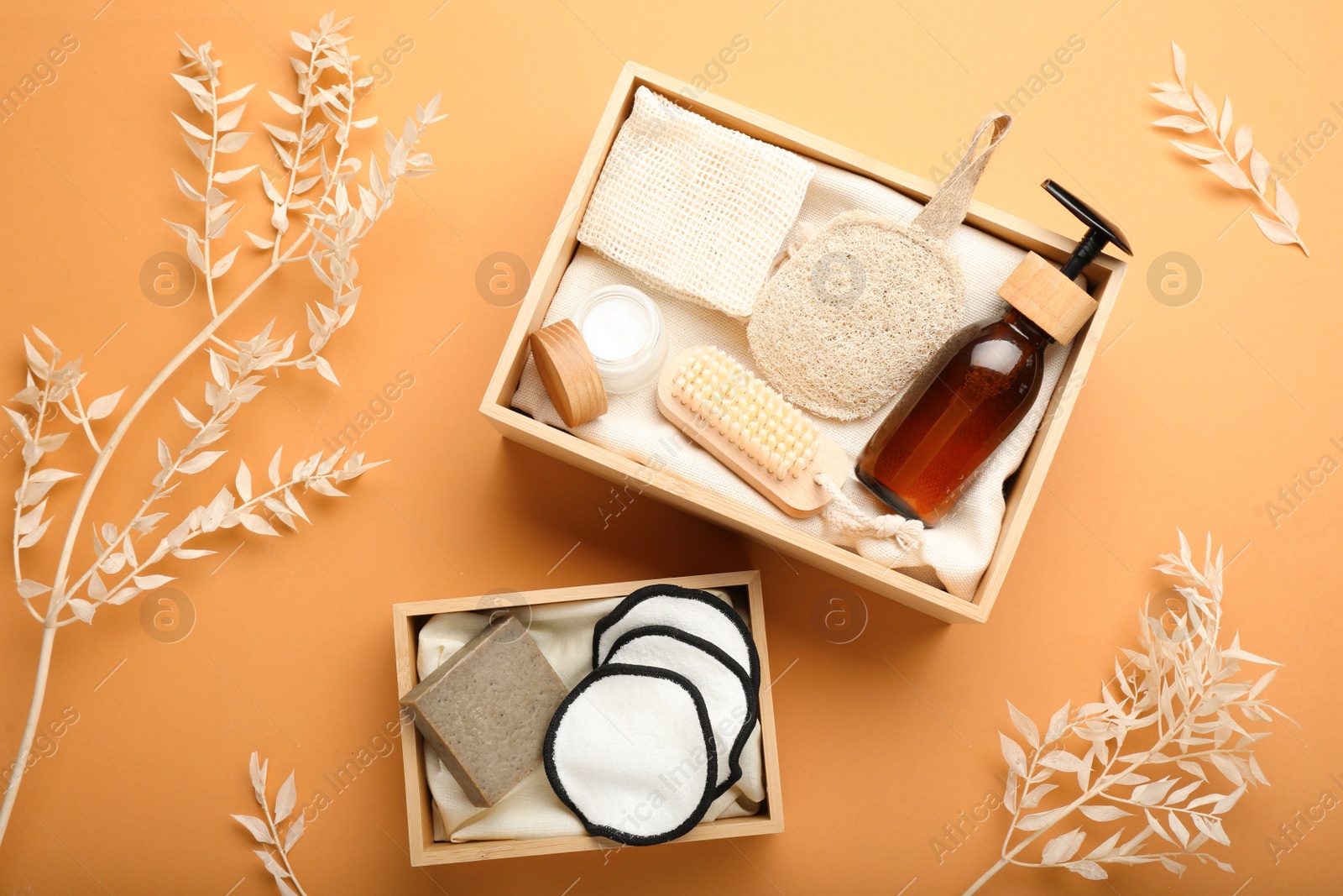Photo of Eco friendly products in crates on pale orange background, flat lay