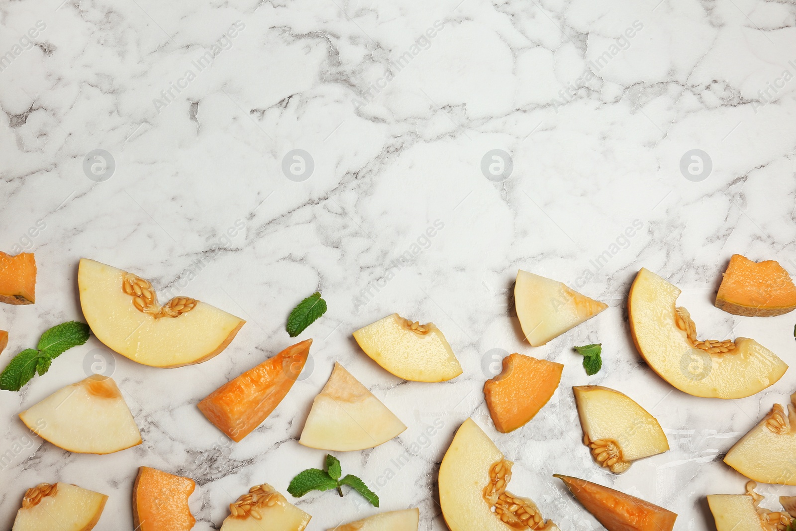 Photo of Flat lay composition with cut tasty melons on table. Space for text