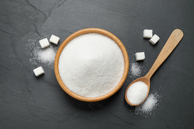 Photo of Flat lay composition with granulated sugar on dark table