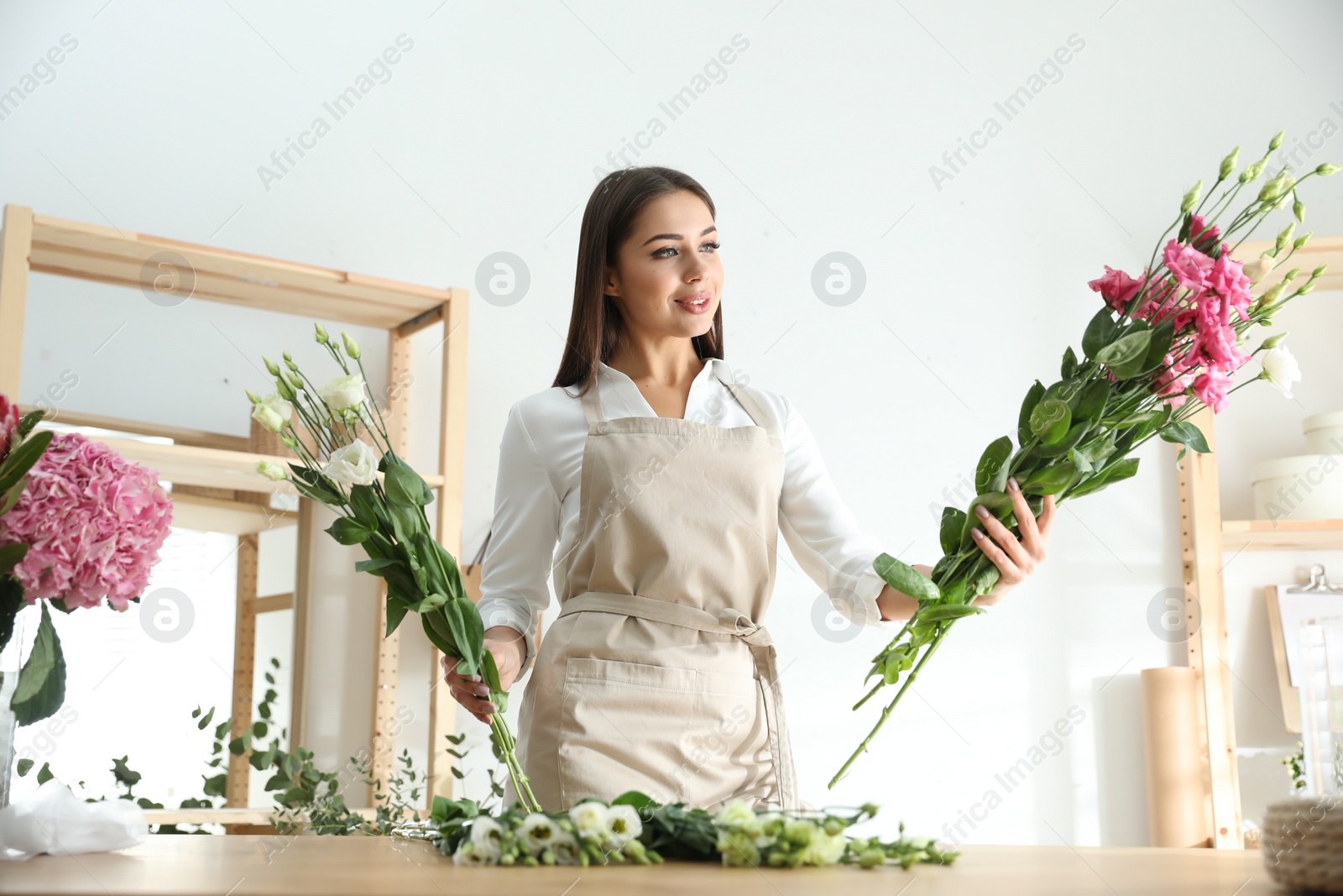 Photo of Florist making beautiful bouquet at table in workshop