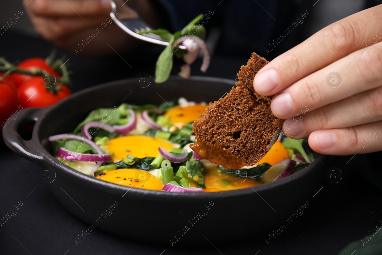 Photo of Woman dipping piece of bread into egg yolk, closeup. Eating tasty Shakshuka