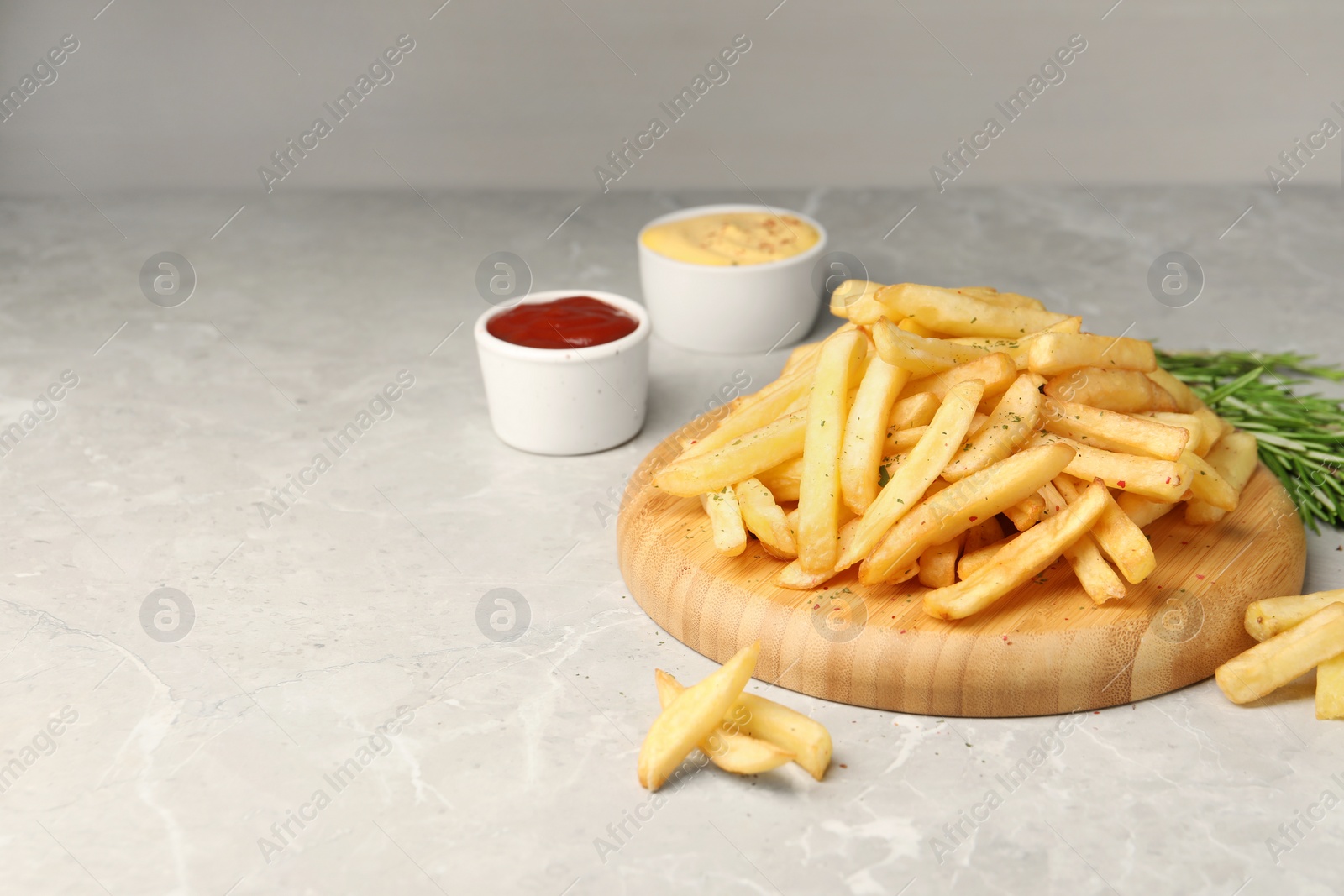 Photo of Delicious french fries served with sauces on light grey marble table, space for text