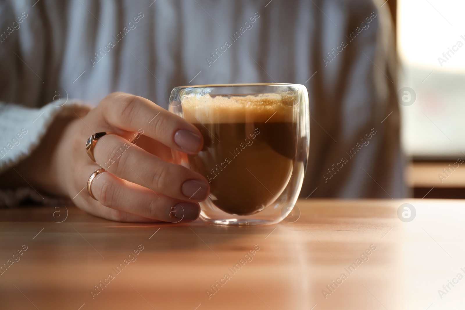 Photo of Woman with aromatic coffee at table in cafe, closeup