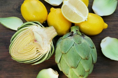 Photo of Artichokes and lemons on wooden table, above view