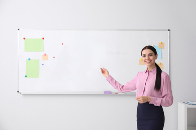 Photo of Young teacher near whiteboard in modern classroom. Space for text