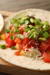 Photo of Delicious taco with vegetables, green onion, lime and ketchup on table, closeup