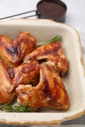 Photo of Marinated chicken wings and rosemary on white table, closeup