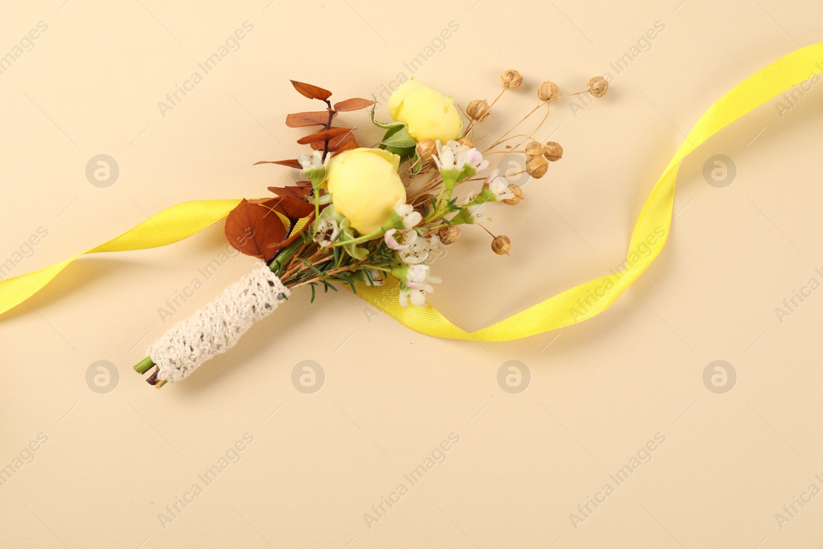 Photo of Stylish boutonniere and ribbon on beige background, top view