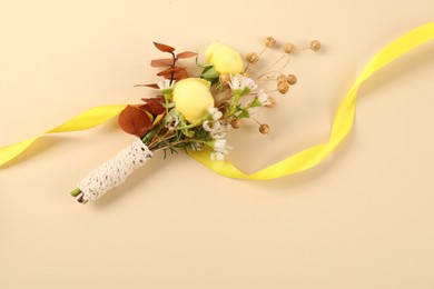 Stylish boutonniere and ribbon on beige background, top view