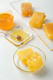 Photo of Natural honeycombs with tasty honey and dipper on white table, above view
