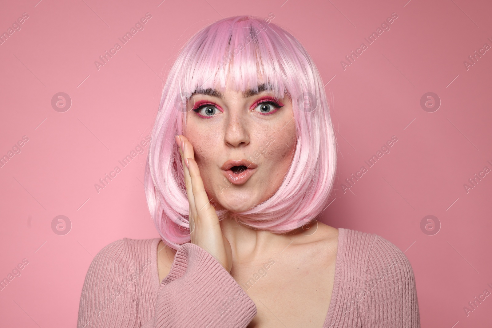 Photo of Surprised woman with bright makeup and fake freckles on pink background
